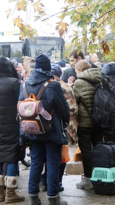 Viele Menschen versammeln sich vor einem Bus, um die Stadt Oleschky zu verlassen.