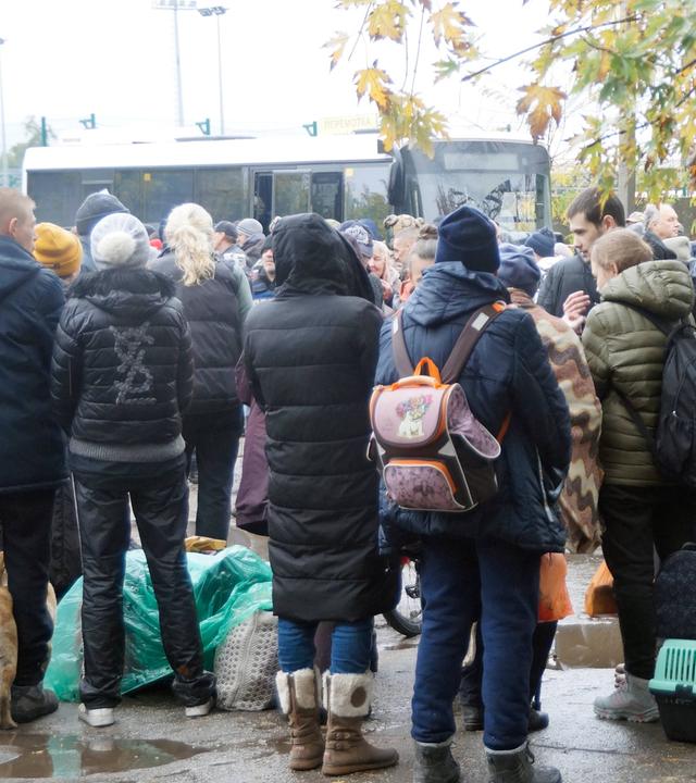 Viele Menschen versammeln sich vor einem Bus, um die Stadt Oleschky zu verlassen.