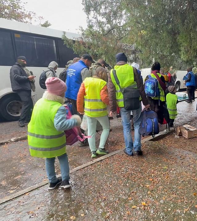 Kinder und Erwachsene gehen am 30.10.2026 zu einem Bus in Oleschky, Ukraine, um aus der Stadt evakuiert zu werden.