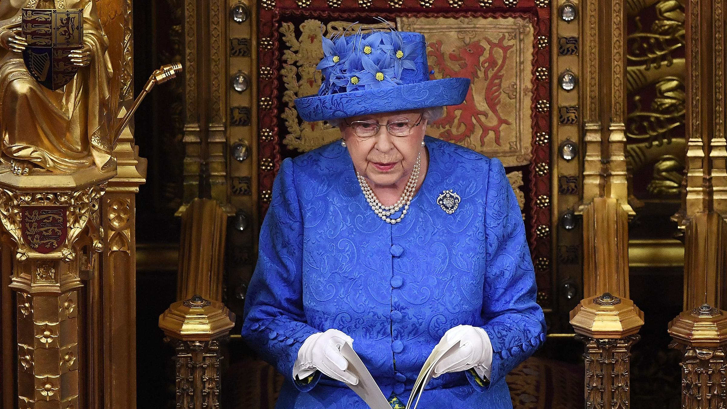 Das Bild zeigt Queen Elizabeth II mit einem blauen Hut mit gelben Blüten