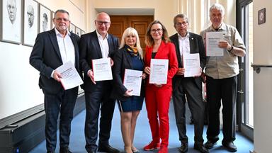 Berlin: Kommissionsmitglieder Uwe Nerger (l-r), Kai Wegner (CDU), Iris Spranger (SPD), Sigrid Nikutta, Heyo Kroemer und Albrecht Broemme, stehen nach der Pressekonferenz der Expertenkommission zum großen Stromausfall Anfang des Jahres 2026 nebeneinander und halten den Bericht in der Hand.