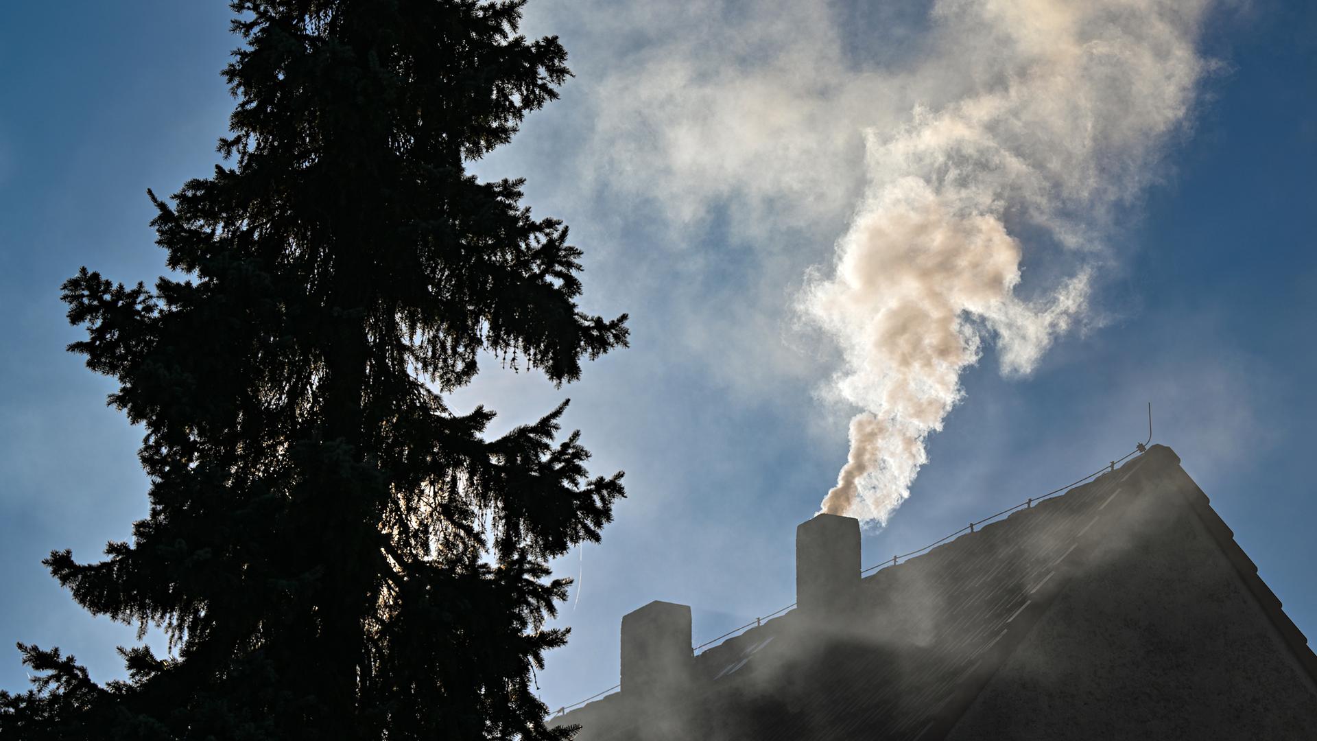 Qualm steigt aus einem Schornstein eines Einfamilienhauses.