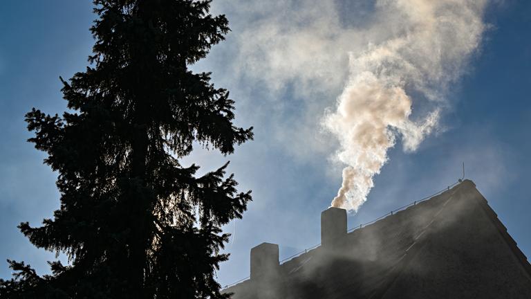 Qualm steigt aus einem Schornstein eines Einfamilienhauses.