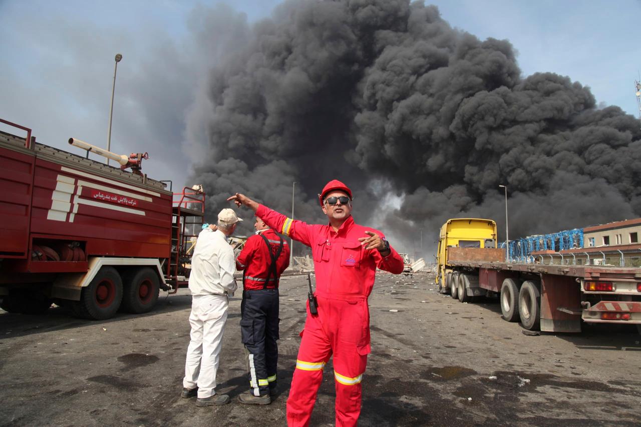 Ein Feuerwehrmann steht vor dem schwarzem Rauch im Hafen von Schahid Radschaei.