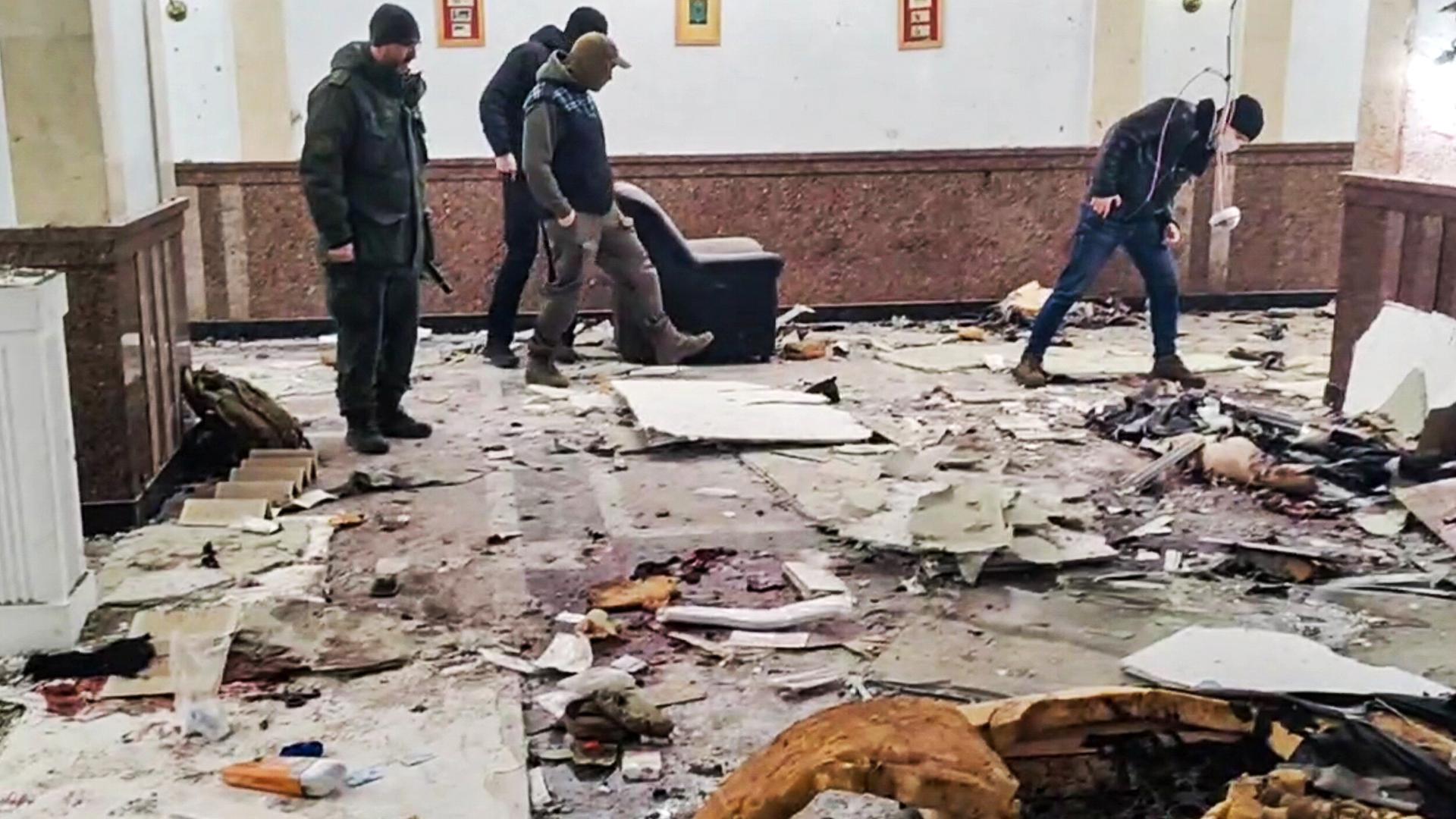 Männer sind im Eingangsbereich des Wohnkomplexes Alyye Parusa zu sehen, nachdem eine Explosion durch einen unbekannten Sprengsatz verursacht wurde