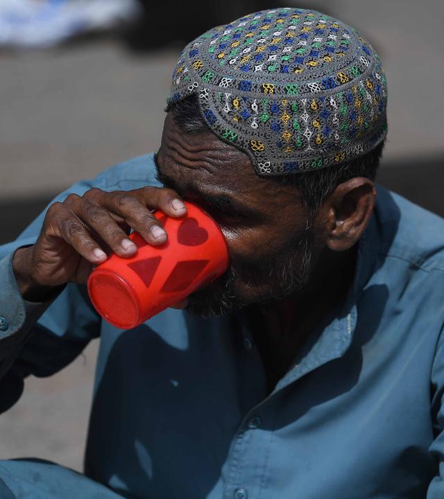 Ein Mann erfrischt sich, während Freiwillige am Straßenrand in Karatschi (Pakistan) am 11. Juni 2026 Trinkwasser verteilen