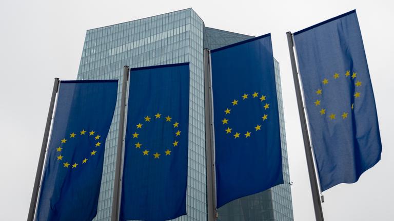 Vier EU-Flaggen aus Froschperspektive vor dem Hochhaus der Europäischen Zentralbank in Frankfurt