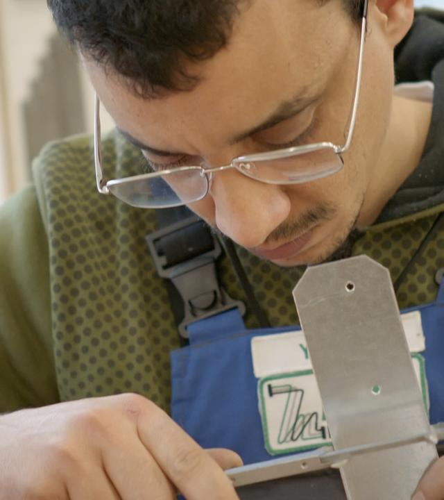 Junger Mann bearbeutet Metallstück