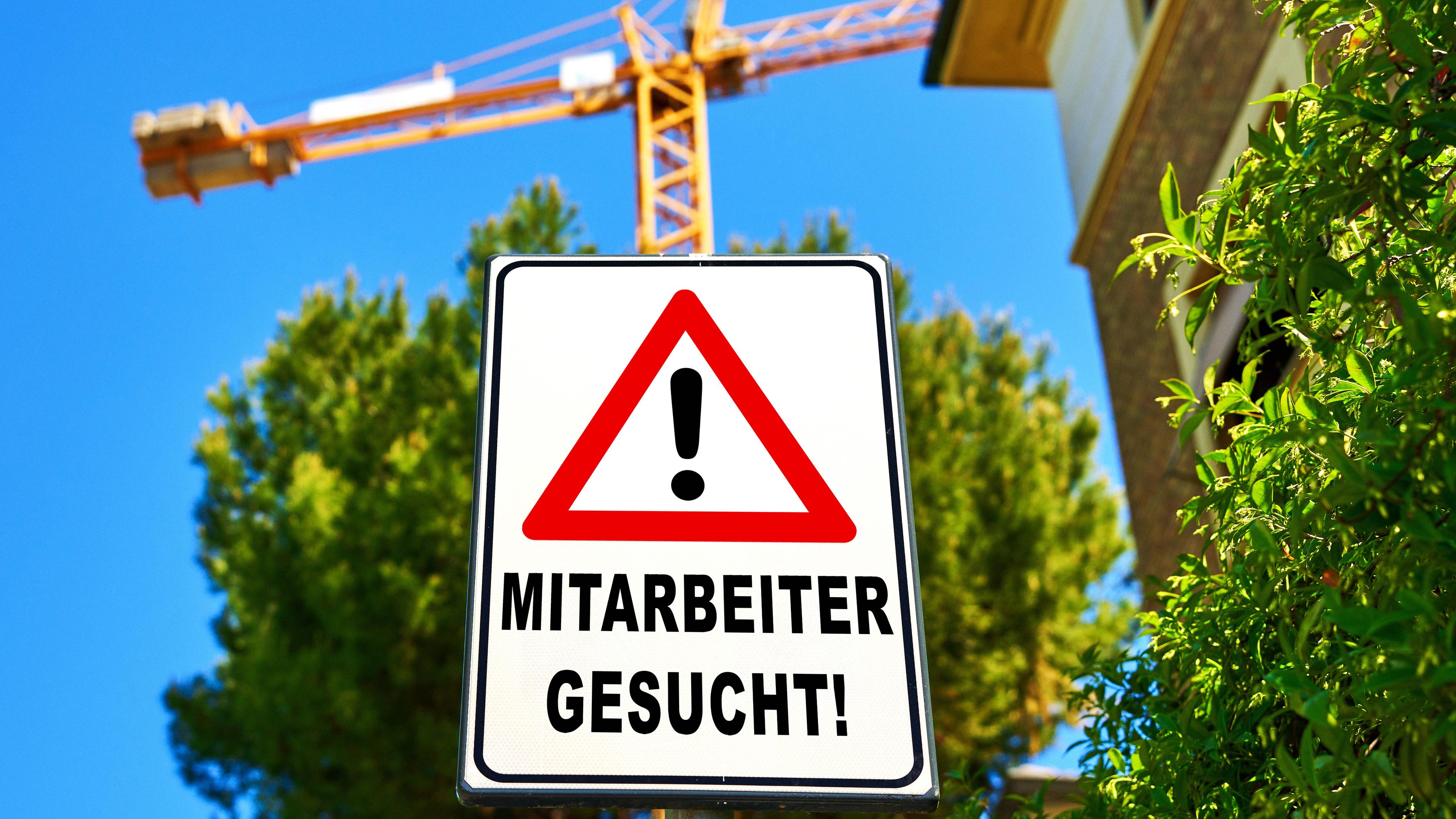 Ein Warnschild mit der Aufschrift: Mitarbeiter gesucht! an einer Baustelle