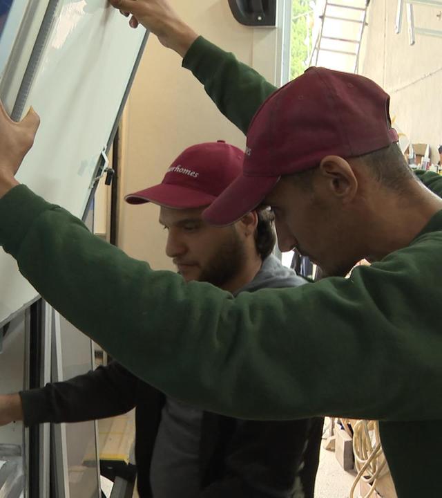 Zwei Männer in einem Betrieb arbeiten zusammen an einem Werkstück.
