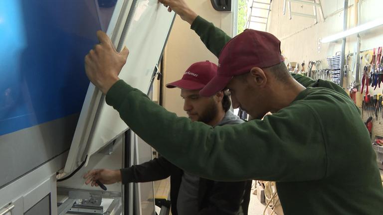 Zwei Männer in einem Betrieb arbeiten zusammen an einem Werkstück.