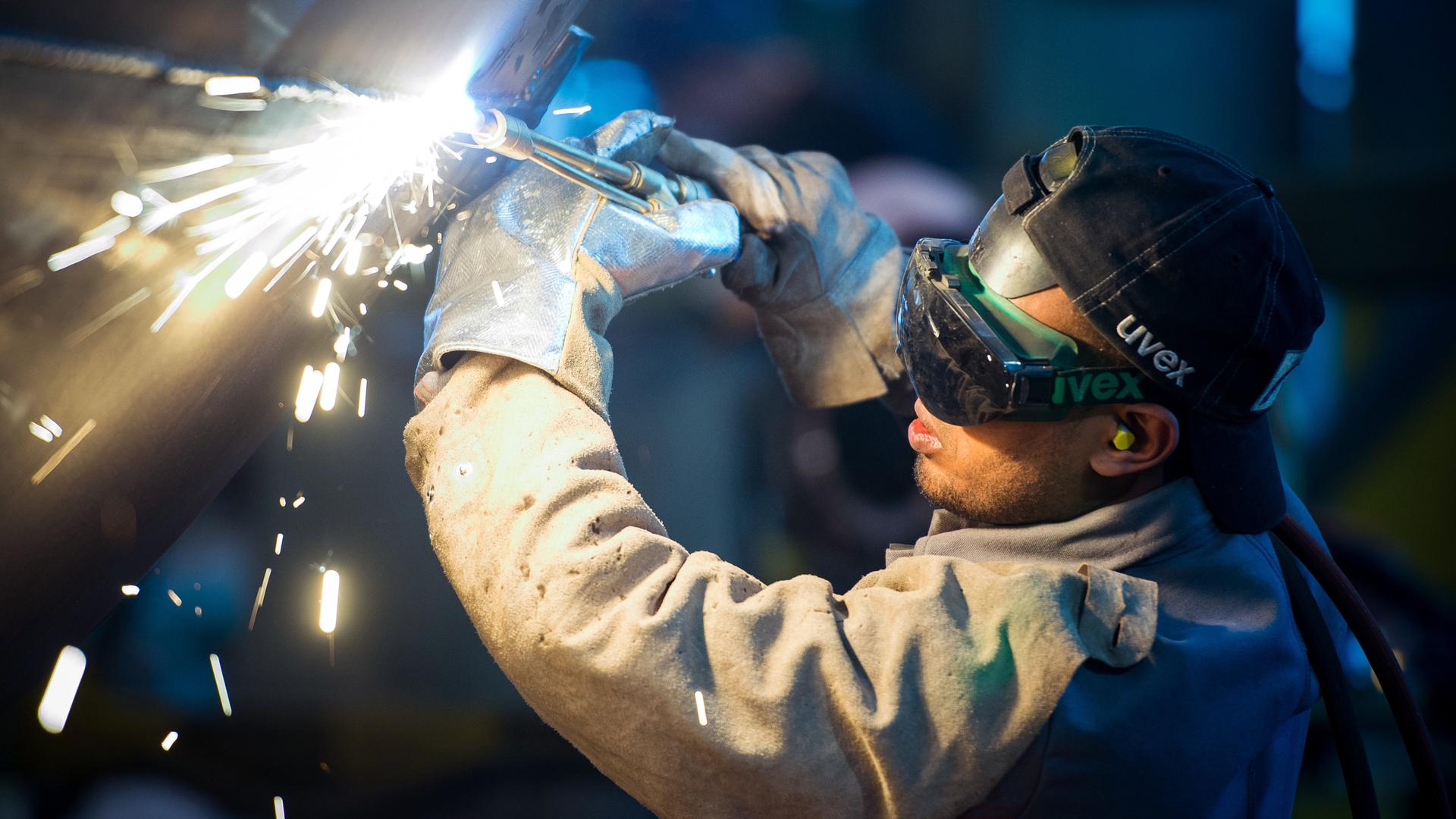 Eine zuvor als Schweißer ausgebildete Person arbeitet an einem Stahlsegement für einen Windradturm. Fürstenwalde, Brandenburg.