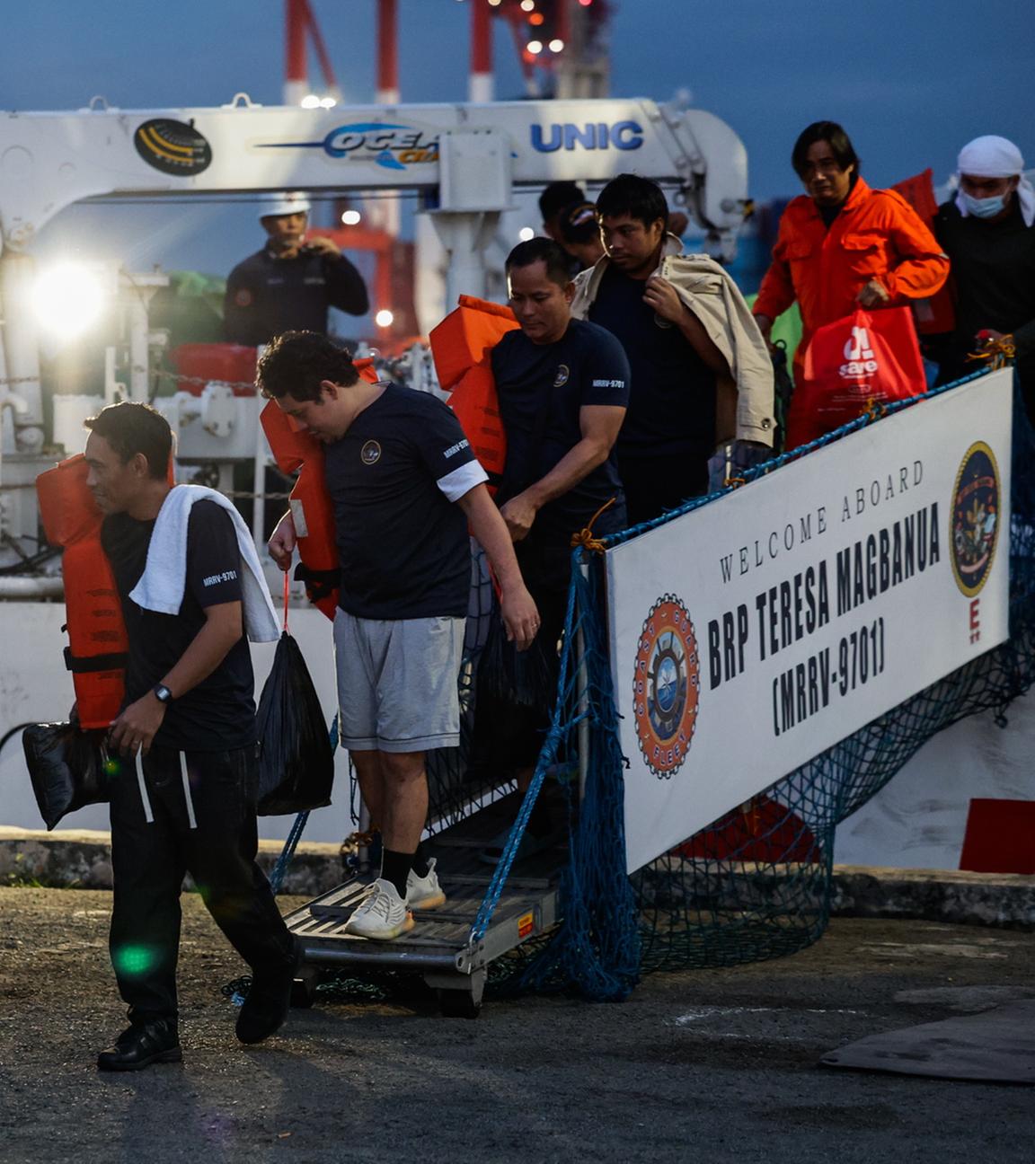 Philippinische Besatzungsmitglieder des Frachtschiffs M/V Devon Bay gehen am 26.01.2026 im Hafen von Manila, Philippinen, von einem Schiff der philippinischen Küstenwache (PCG) an Land. 