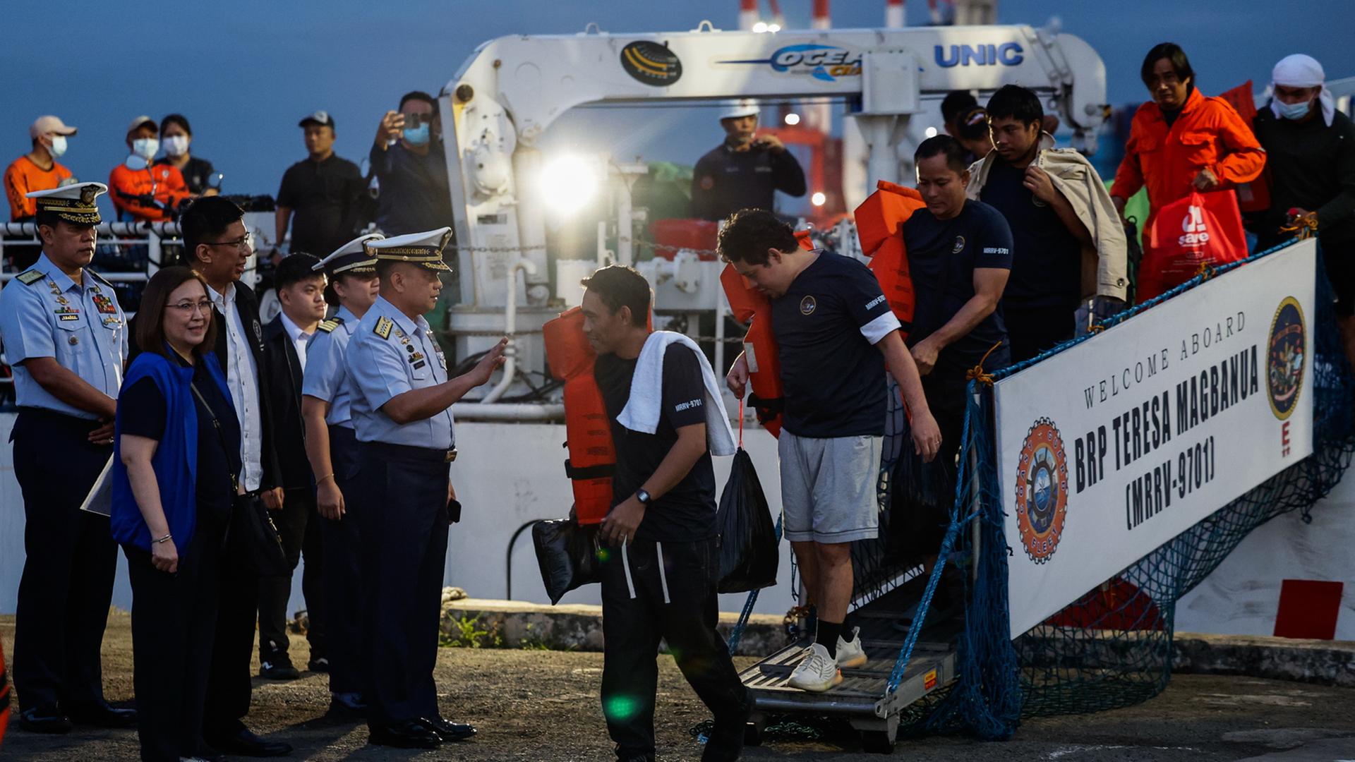Philippinische Besatzungsmitglieder des Frachtschiffs M/V Devon Bay gehen am 26.01.2026 im Hafen von Manila, Philippinen, von einem Schiff der philippinischen Küstenwache (PCG) an Land. 