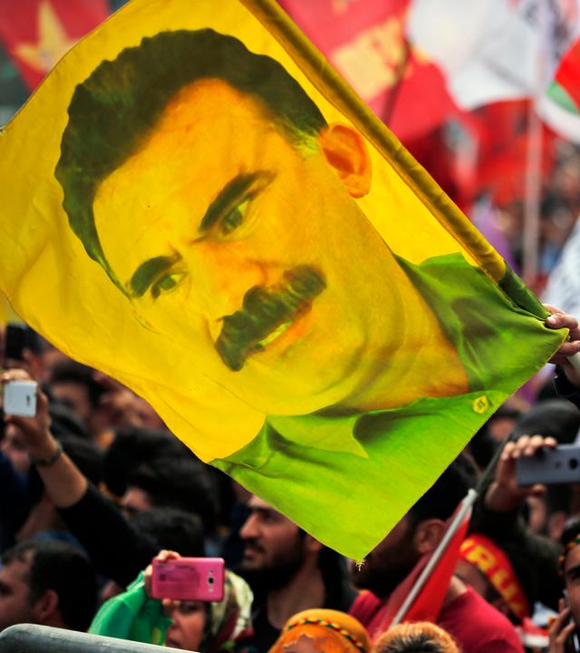 Ein Jugendlicher hält eine Fahne mit dem Bild des inhaftierten Anführers der verbotenen kurdischen Arbeiterpartei PKK, Öcalan.  
