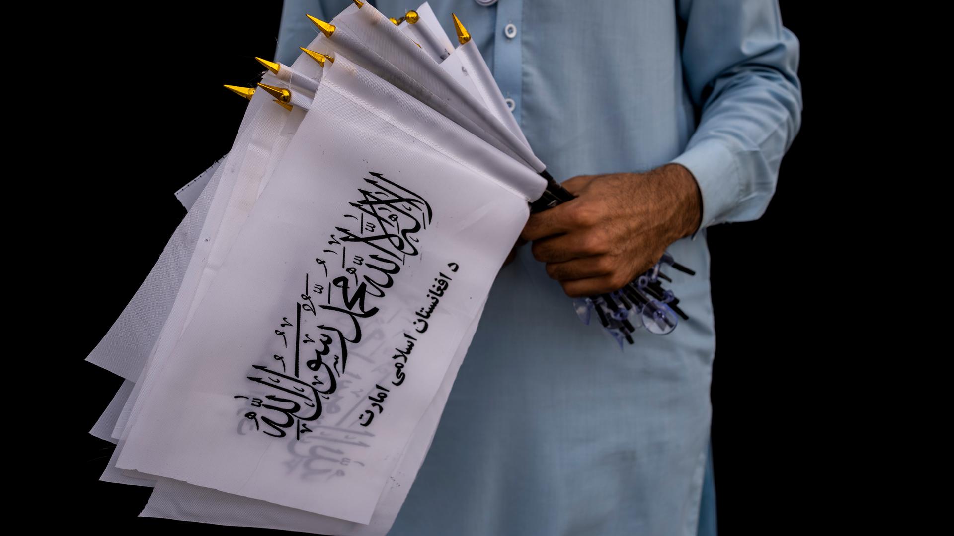 Ein Mann hält Taliban-Fahnen in der Hand (Archivbild) 