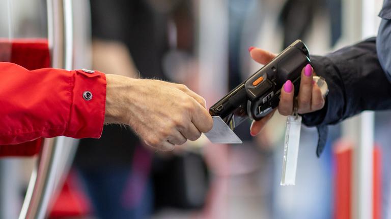 Eine Fahrkartenkontrolleurin (r) kontrolliert mit einem elektronischen Lesegerät in der Nürnberger U-Bahn den Fahrschein eines Fahrgastes