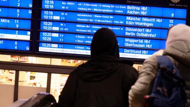 Nordrhein-Westfalen, Berlin: Reisende betrachten im Hauptbahnhof eine Anzeigetafel