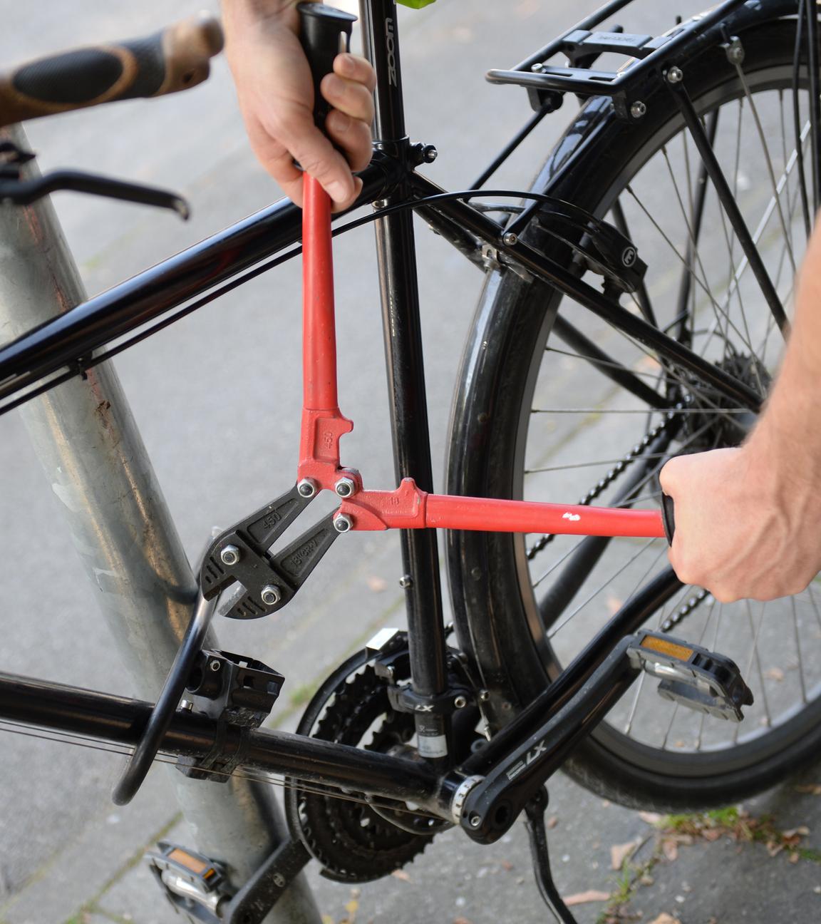 Ein Mann versucht mit einem Bolzenschneider ein Fahrradschloss aufzubrechen