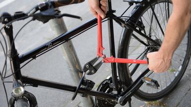 Ein Mann versucht mit einem Bolzenschneider ein Fahrradschloss aufzubrechen