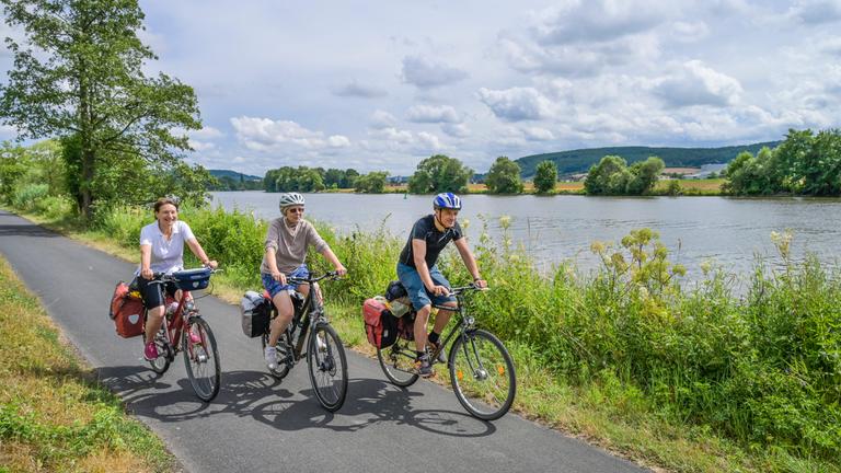 Fahrradfahrer radlen am Ufer auf dem Main-Radweg bei Karlstadt in Bayern.