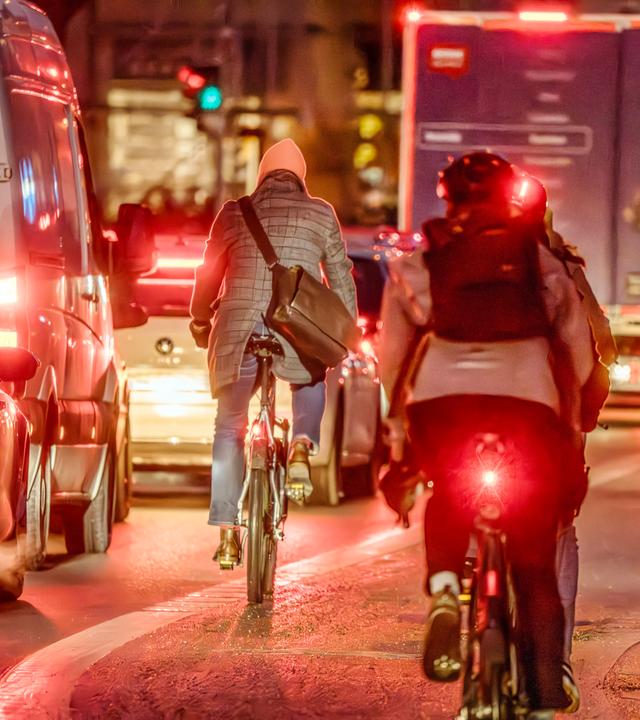 Rücklichter von Fahrradfahrern im Straßenverkehr bei Dunkelheit