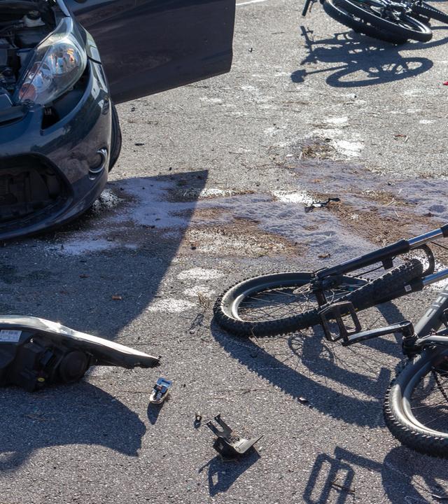Symbolbild: Fahrräder liegen neben einem Auto auf der Straße.