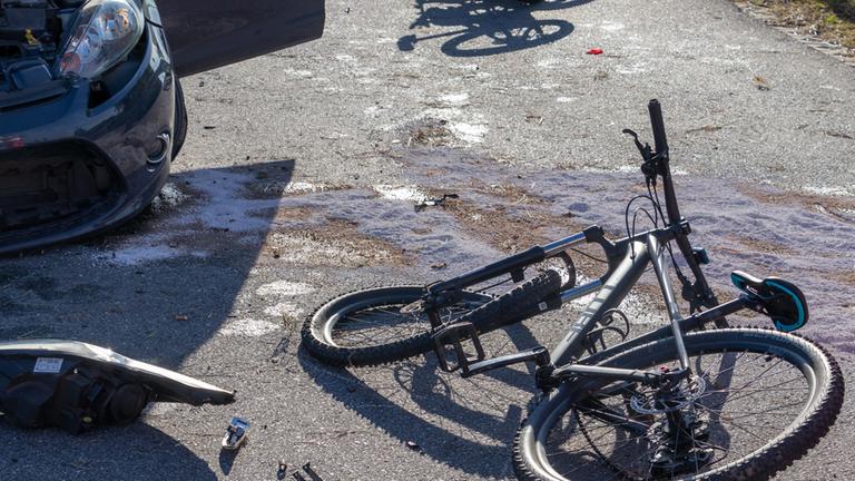 Symbolbild: Fahrräder liegen neben einem Auto auf der Straße.