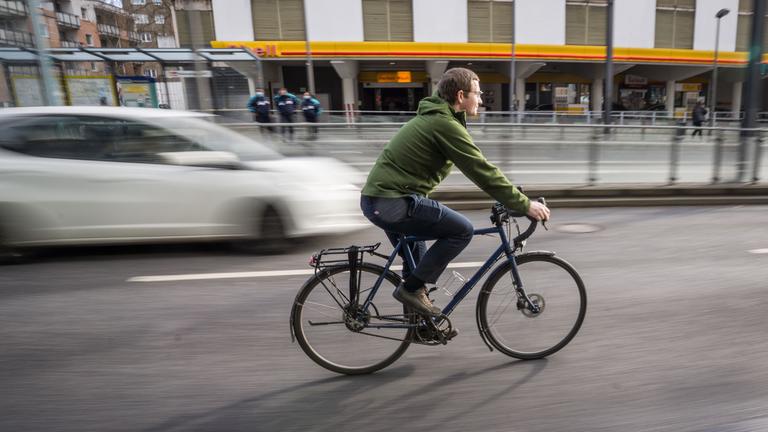 Fahrradfahrer auf Fahrradweg  neben Autos
