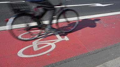 Ein Fahrradfahrer fährt auf einem rot abgegrenzten Radweg mit Fahrrad-Piktogramm.