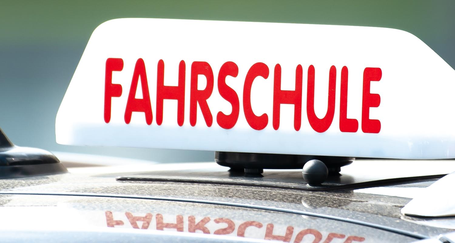  Ein Schild mit der Aufschrift «Fahrschule» ist auf einem Fahrschulauto befestigt. 