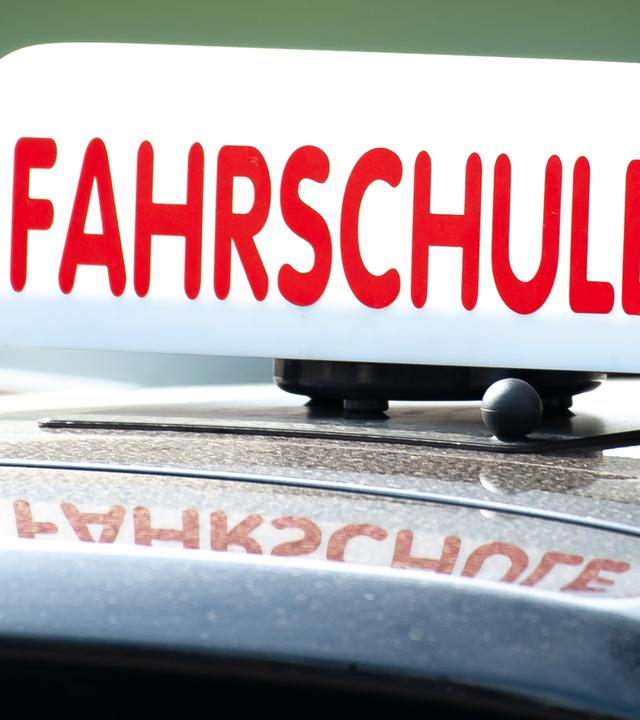  Ein Schild mit der Aufschrift «Fahrschule» ist auf einem Fahrschulauto befestigt. 