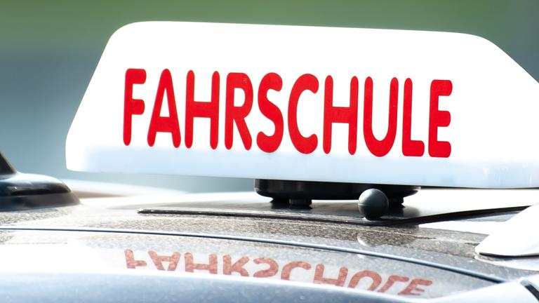  Ein Schild mit der Aufschrift «Fahrschule» ist auf einem Fahrschulauto befestigt. 