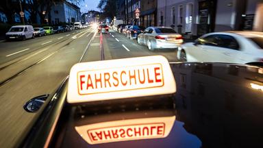 Abendliche Fahrt in einer Innenstadt mit einem Fahrschulauto.