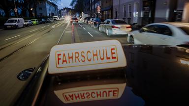Abendliche Fahrt in einer Innenstadt mit einem Fahrschulauto.