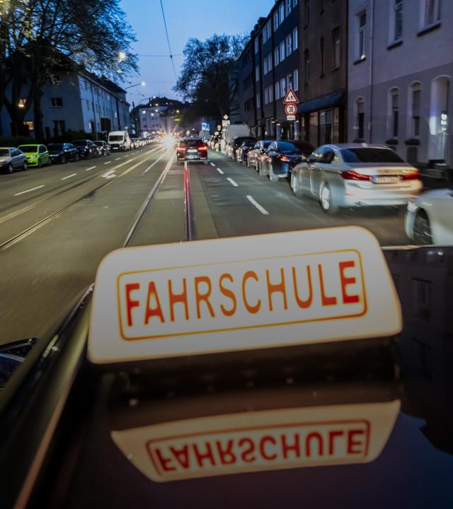 Abendliche Fahrt in einer Innenstadt mit einem Fahrschulauto.