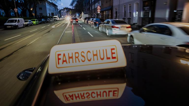 Abendliche Fahrt in einer Innenstadt mit einem Fahrschulauto.
