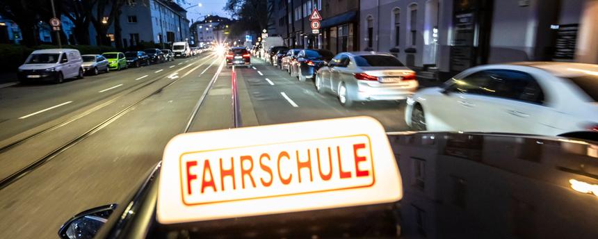 Abendliche Fahrt in einer Innenstadt mit einem Fahrschulauto.