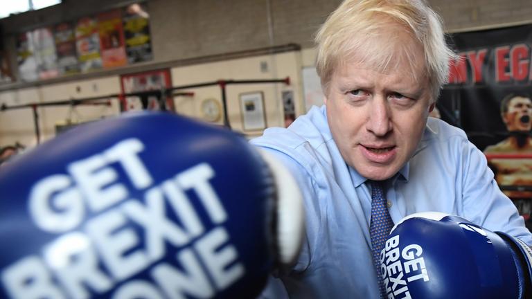 Boris Johnson mit Boxhandschuhen, die den Schriftzug "GET BREXIT DONE" tragen. Er streckt die rechte Faust vor.