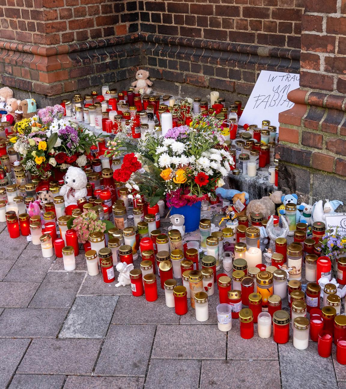 Vor der Marienkirche stehen Grablichter, Blumen und Plüschtiere im Gedenken an den vermissten achtjährigen Fabian, auf einem Schild steht "In Trauer um Fabian". 