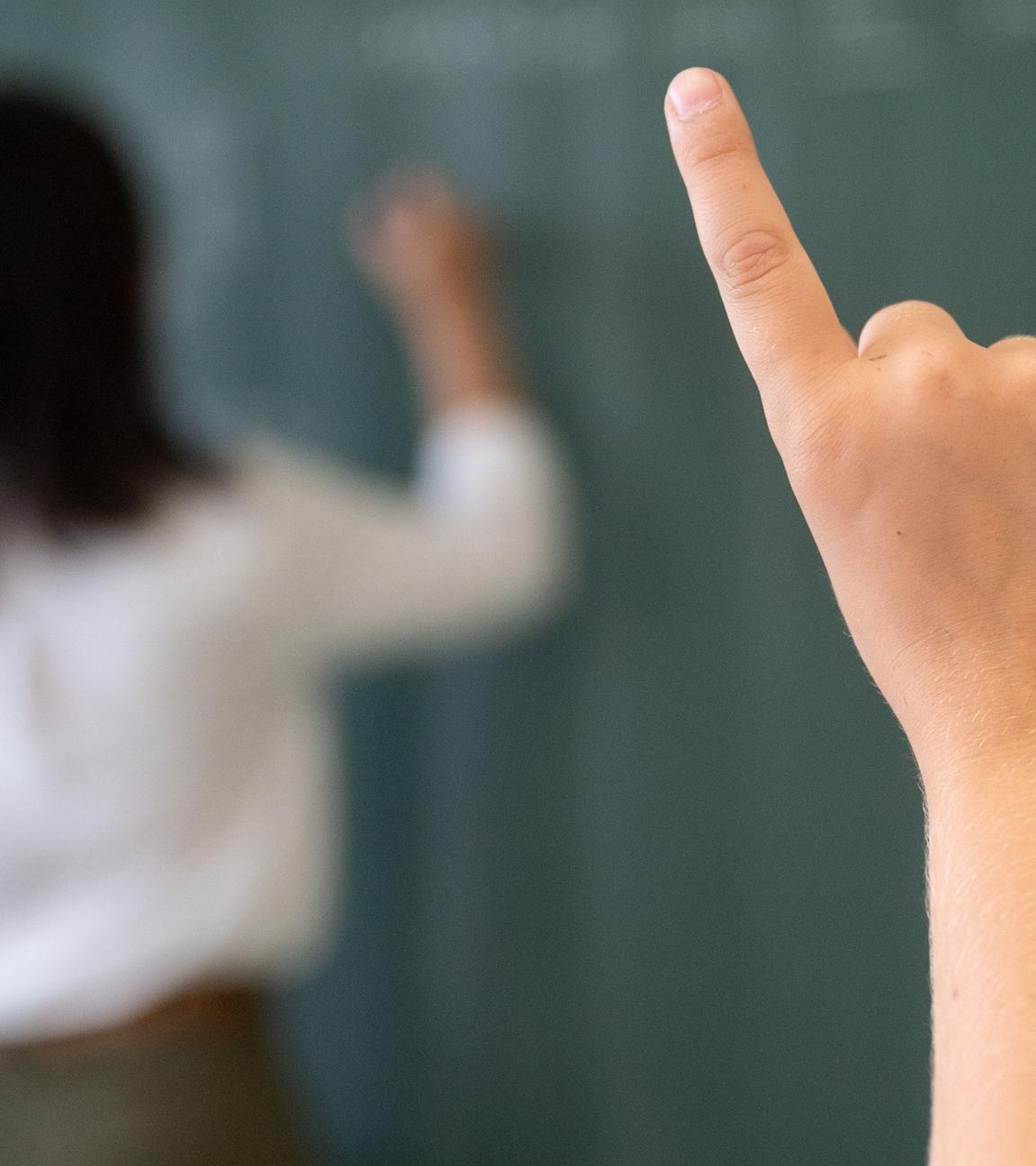 08.07.2020, Baden-Württemberg, Marbach am Neckar: Ein Schüler meldet sich während einer Unterrichtsstunde einer fünften Klasse des Friedrich-Schiller Gymnasiums, während die Lehrerin an die Tafel schreibt. 