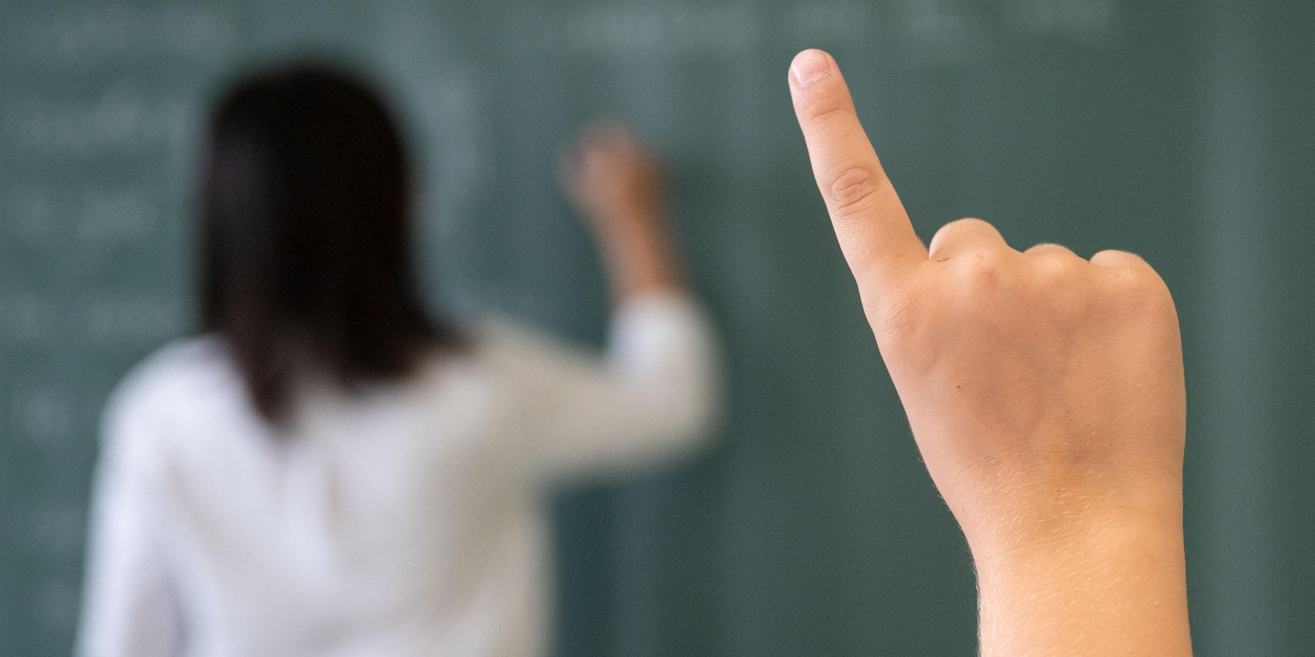 08.07.2020, Baden-Württemberg, Marbach am Neckar: Ein Schüler meldet sich während einer Unterrichtsstunde einer fünften Klasse des Friedrich-Schiller Gymnasiums, während die Lehrerin an die Tafel schreibt. 