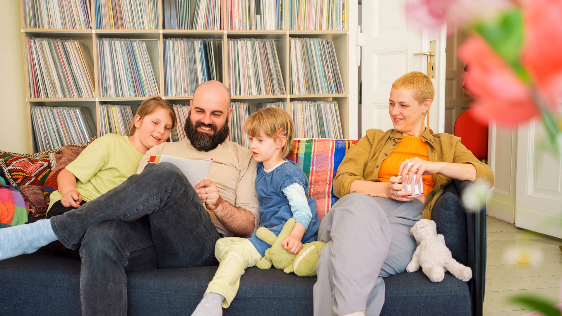 Familie sitzt auf Couch vor Bücherregal 