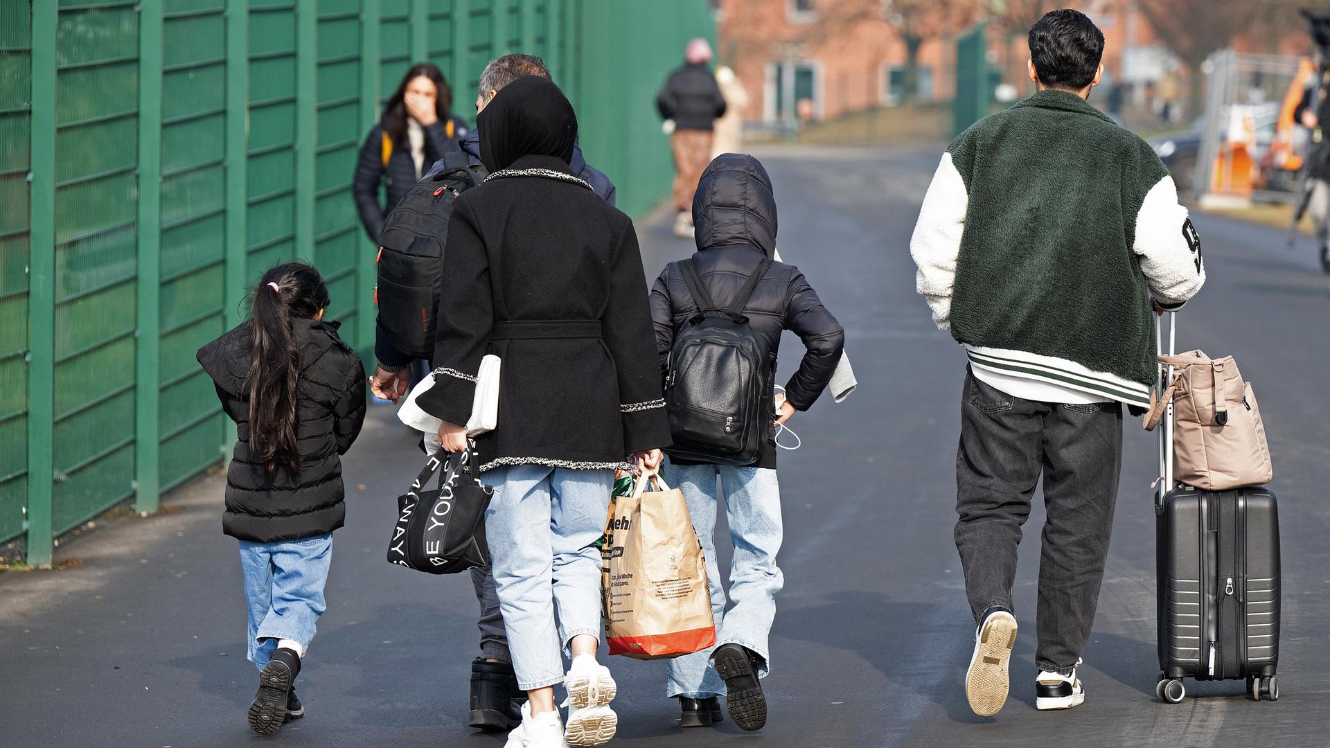 Flüchtlinge gehen in der Erstaufnahmeeinrichtung für Flüchtlinge in Gießen zu einer Unterkunft.