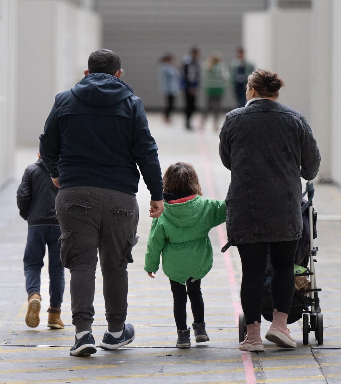 Eine Flüchtlingsfamilie geht durch die zu einer Massenunterkunft umfunktionierten Messehalle in Frankfurt. (Archivbild) 
