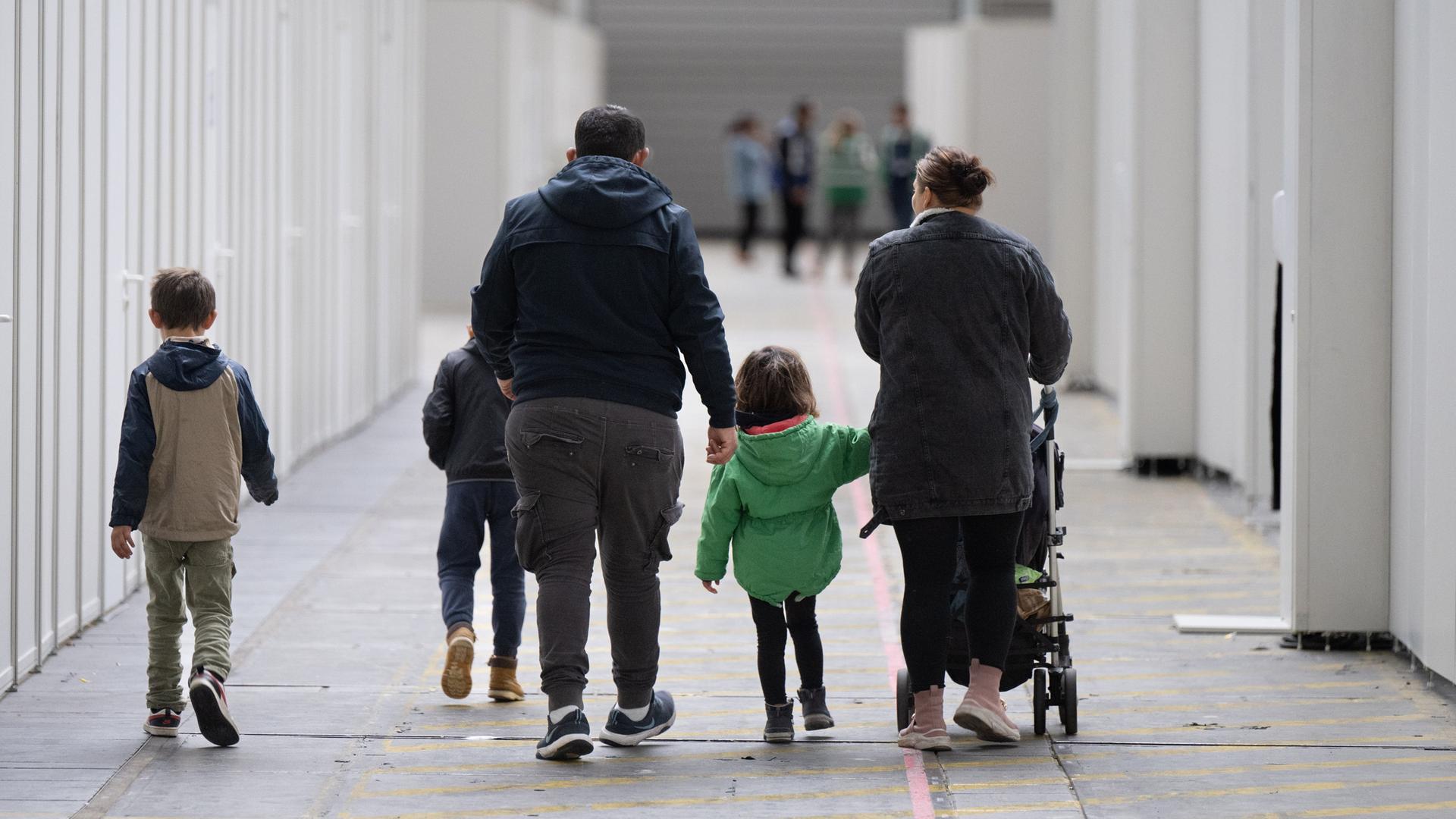 Eine Flüchtlingsfamilie geht durch die zu einer Massenunterkunft umfunktionierten Messehalle in Frankfurt. (Archivbild) 