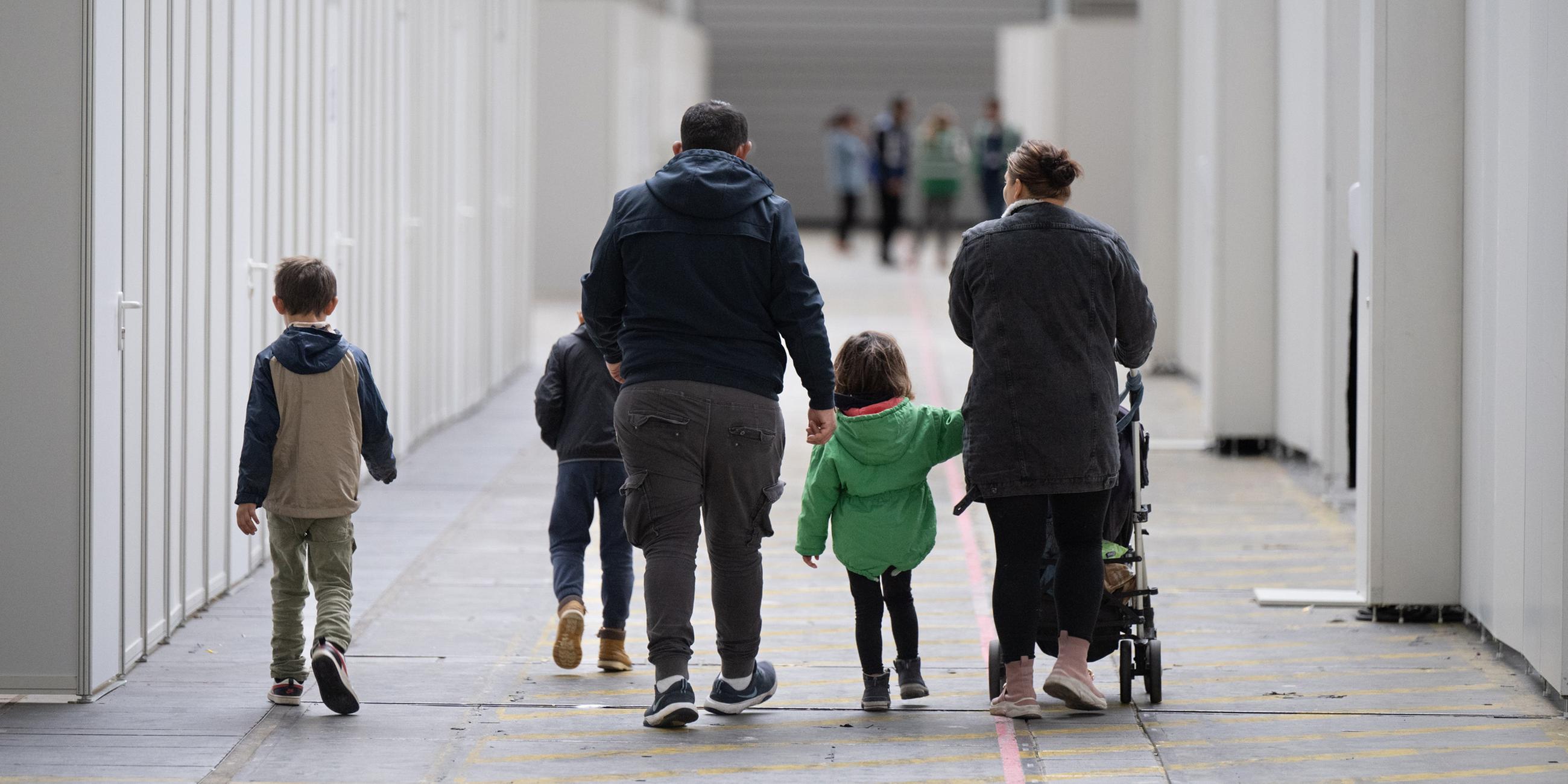 Eine Flüchtlingsfamilie geht durch die zu einer Massenunterkunft umfunktionierten Messehalle in Frankfurt. (Archivbild) 
