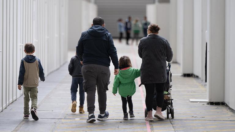 Eine Flüchtlingsfamilie geht durch die zu einer Massenunterkunft umfunktionierten Messehalle in Frankfurt. (Archivbild) 