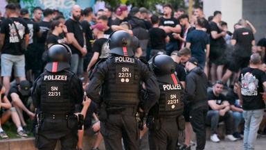 Einsatzkräfte der Polizei bewachen eine Gruppe Fußballfans in der Innenstadt von Leipzig