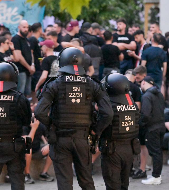 Einsatzkräfte der Polizei bewachen eine Gruppe Fußballfans in der Innenstadt von Leipzig